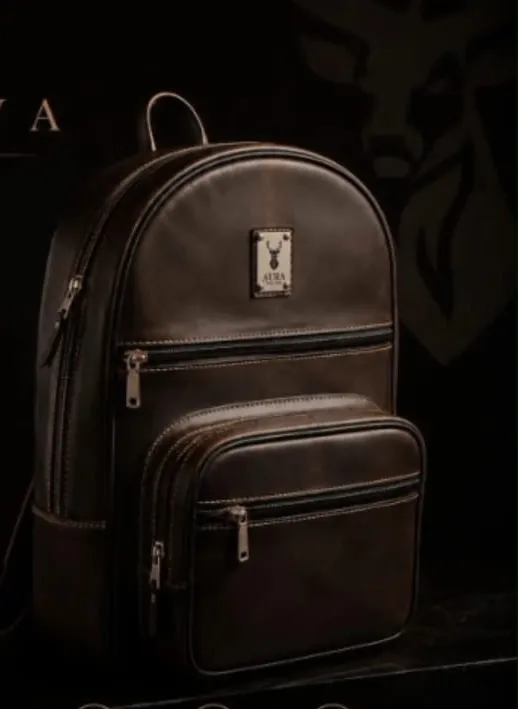 Mochila de cuero AURA NOVA iluminada sobre fondo oscuro, mostrando el acabado encerado del cuero y la silueta redondeada.